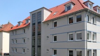 Graues Wohnhaus mit 4 Etagen, Treppenhaus große Fenster, Dach neu.