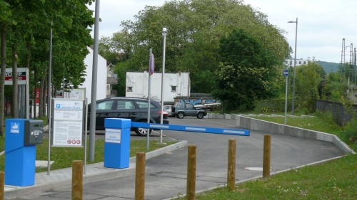 Einfahrt Parkplatz mit Schrankenanlage, parkende Autos.