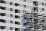 Ausschnitt weiße Fassade mit Loggien, rechts noch Baugerüst.