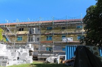 Haus mit drei Etagen wird saniert. Wärmedämmung ist zum Teil schon de rFassade. Davor ein Gerüst.