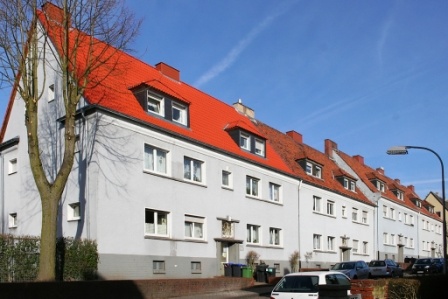 Häuser mit drei Etagen, Dächer neu. Vorgärten mit Wiese, parkende Autos auf Straße. Häuser mit drei Etagen, Dächer neu. Vorgärten mit Wiese, parkende Autos auf Straße.