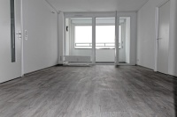 Wohnzimmer mit Blick auf windgeschützte Loggia. Der Vinylbodenbelag ist im Farbton Eiche gekalkt gehalten.