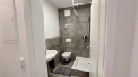 innenliegendes Bad mit Dusche, WC und Waschbecken, dunkel geflammte, große Fliesen