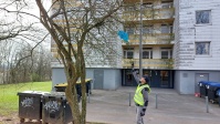 Ein Mitarbeiter versucht, aus einem Baum eine blaue Plastiktüte zu entfernen.