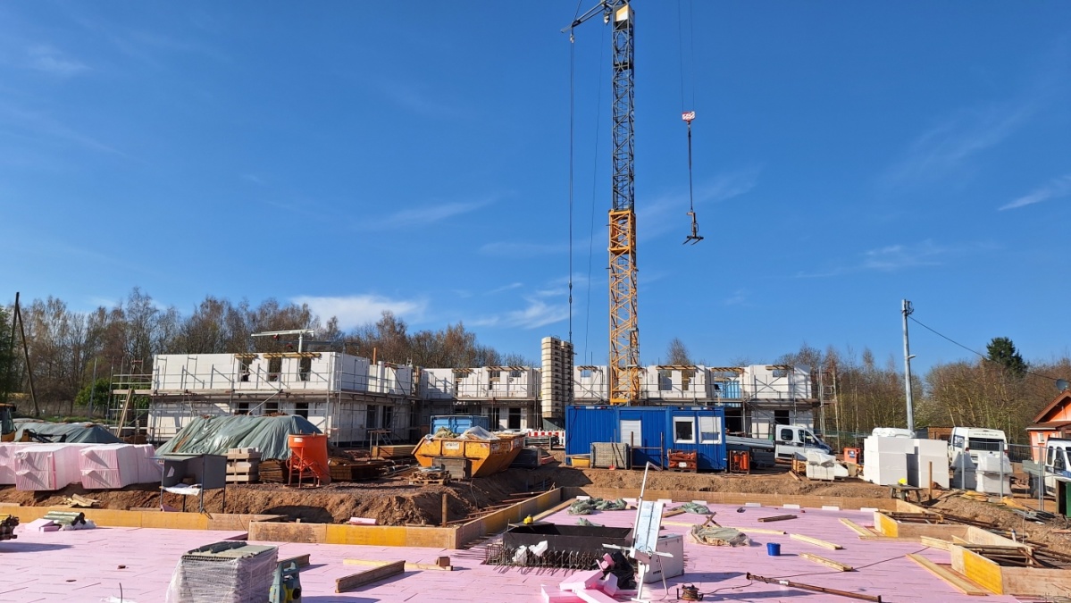 Baustelle mit Bodenplatte 2. Gebäude vorne, in der Mitte Baukran, hinten links Erdgeschoss 1. Gebäude und  Mauern 1. Etage. 